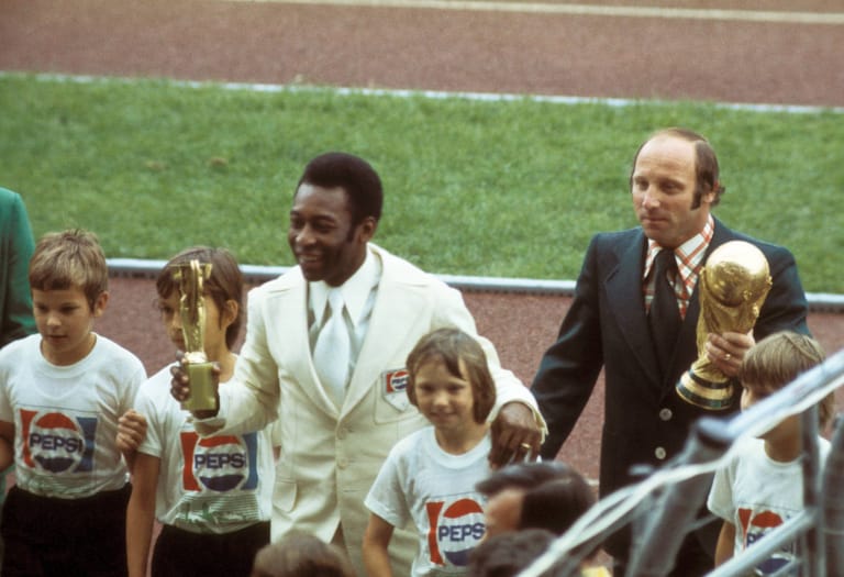 Auftritt bei der Eröffnungsfeier der WM 1974: Pelé, inzwischen nicht mehr Teil der brasilianischen Nationalmannschaft, trägt den Coupe Jules Rimet, der beim Turnier in Deutschland vom Fifa World Cup, den hier Uwe Seeler trägt, abgelöst wurde.