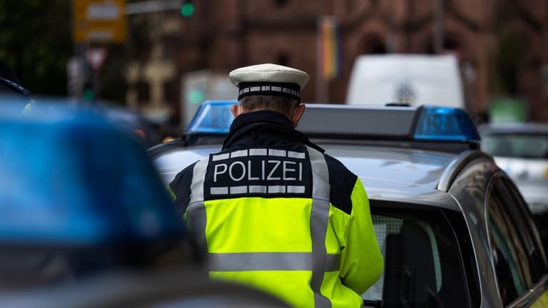 Ein Polizeibeamter steht zwischen zwei Einsatzfahrzeugen der Polizei (Symbolbild): Ein 15-Jähriger war mit dem Auto seines Vaters in Berlin unterwegs.