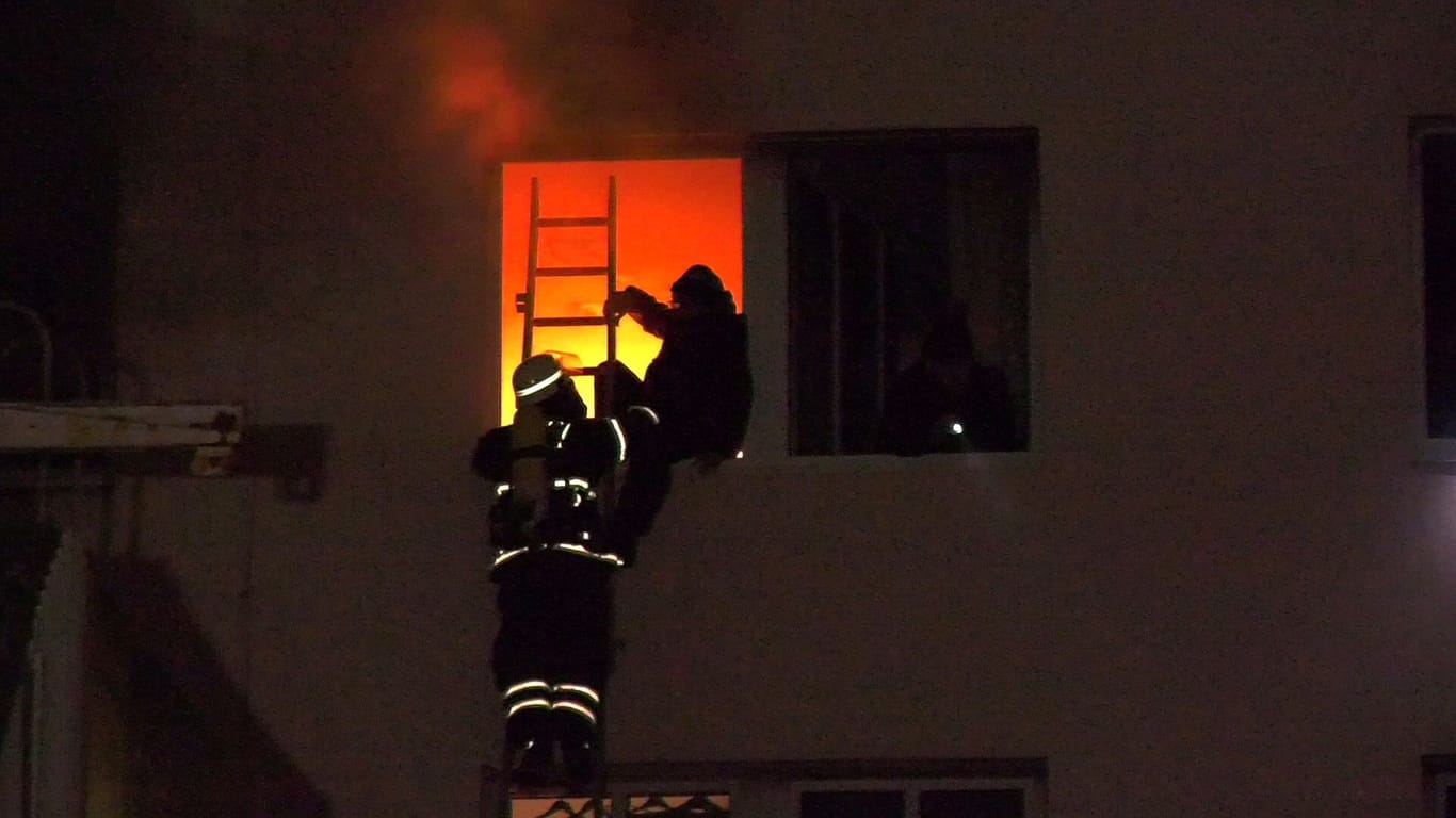 Ein Bewohner wird von der Feuerwehr über eine Drehleiter gerettet: Die Ursache für das Feuer ist noch unklar.