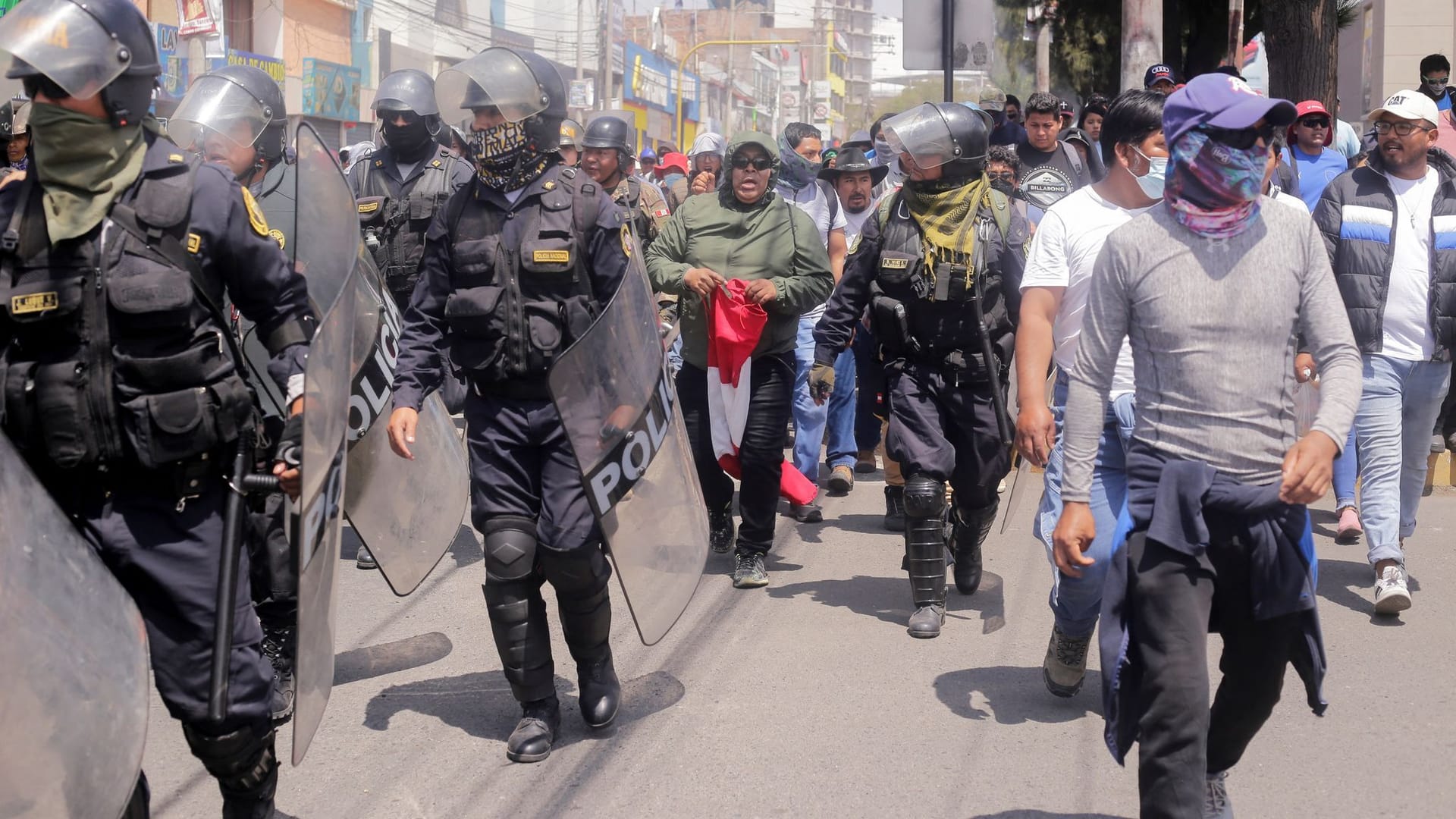 Polizisten neben Demonstranten in Peru: Aufgrund der Unruhen ruft das Land nun einen Ausnahmezustand aus.