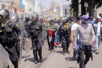 Polizisten neben Demonstranten in Peru: Aufgrund der Unruhen ruft das Land nun einen Ausnahmezustand aus.