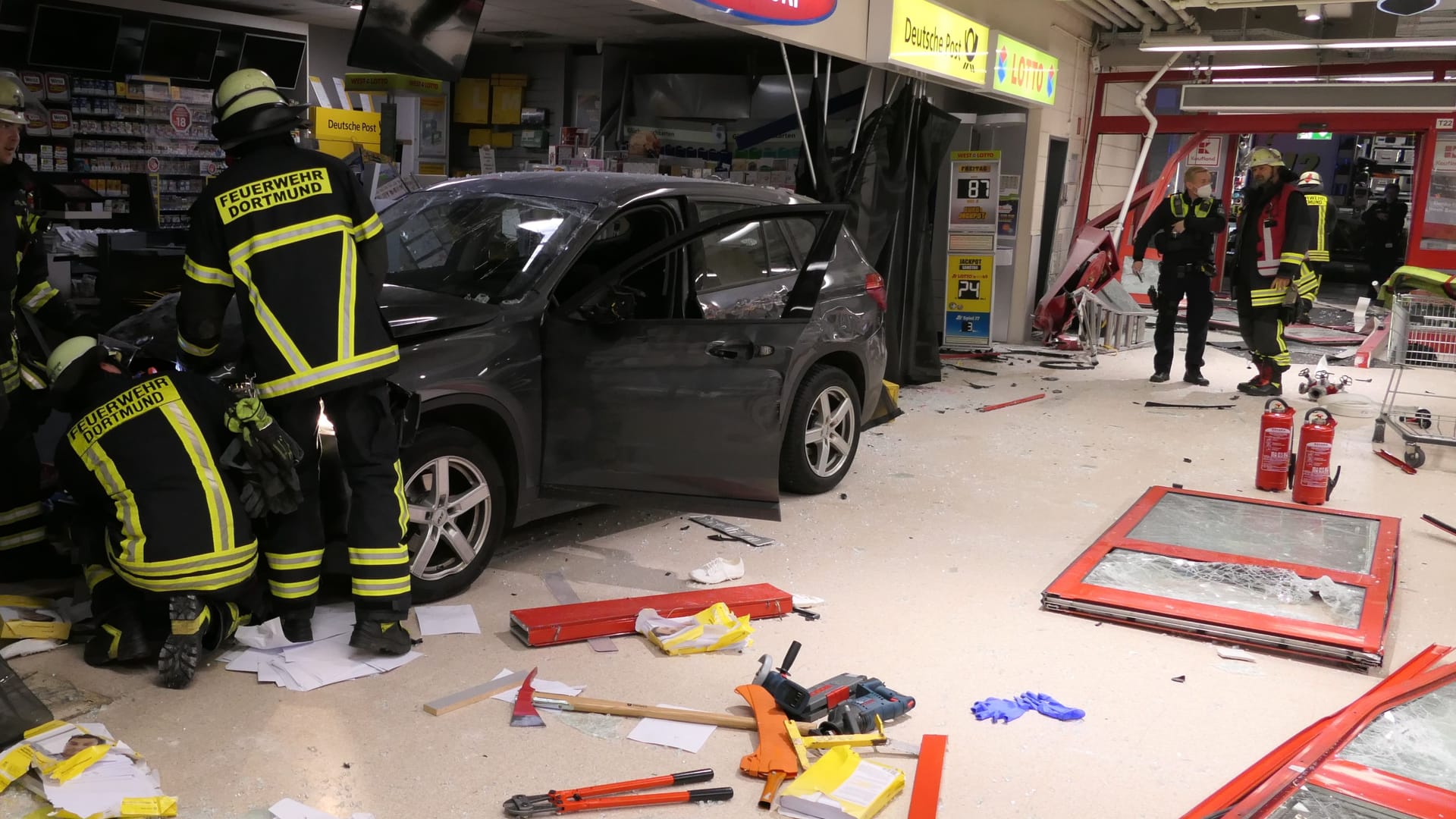 Einsatzkräfte bergen den Wagen: Der PKW kam im Bereich der Ladenlokale im Eingangsbereich zum Stehen.