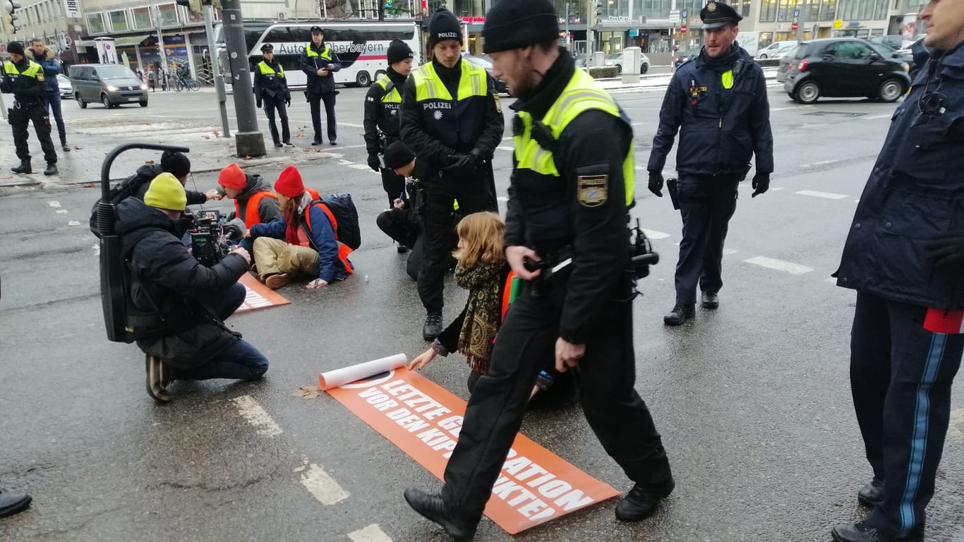 Drei Klimaaktivisten kleben auf der Straße am Stachus in München: Sie blockierten die Straße, obwohl auch die Polizei davon vorab wusste.