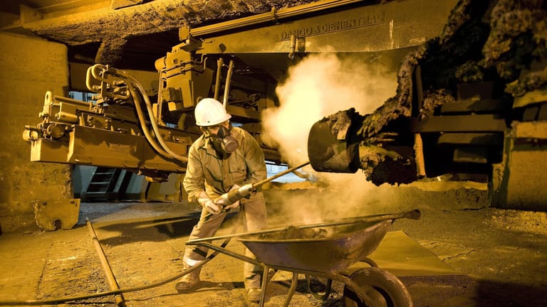 Ein Hochofenarbeiter reinigt ein Anlagenteil im Stahlwerk der Salzgitter AG: Gerade auch im Umgang mit Industriemaschinen stellt Hitze ein zusätzliches Risiko dar.