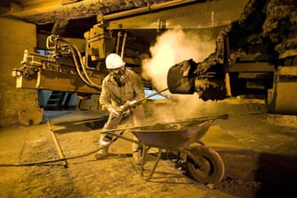 Ein Hochofenarbeiter reinigt ein Anlagenteil im Stahlwerk der Salzgitter AG: Gerade auch im Umgang mit Industriemaschinen stellt Hitze ein zusätzliches Risiko dar.