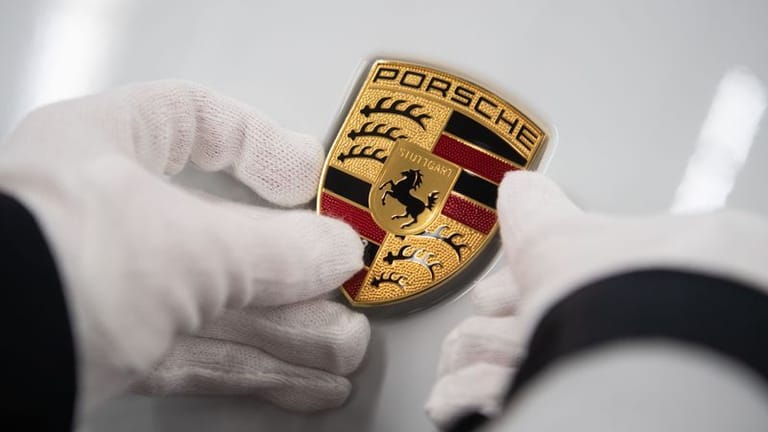 Mitarbeiterin hält in der Produktion ein Porsche-Emblem: Der Börsengang der Volkswagen-Tochter Porsche ist eine Erfolgsgeschichte.
