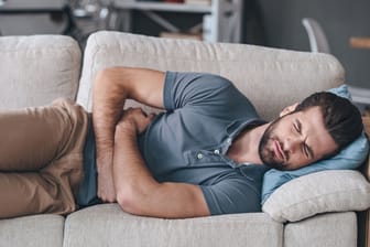Mann mit Bauchschmerzen auf Couch