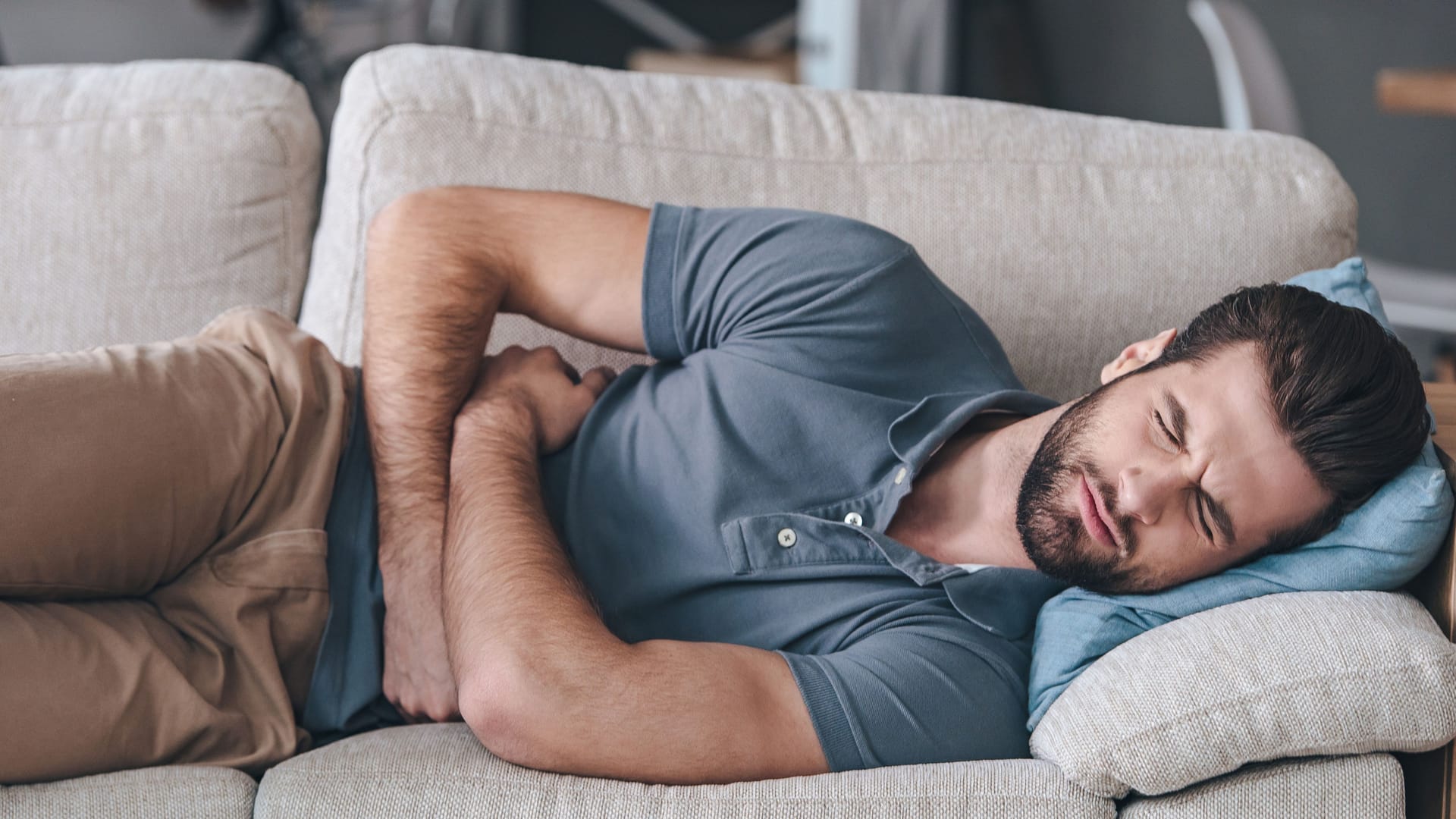 Mann mit Bauchschmerzen auf Couch