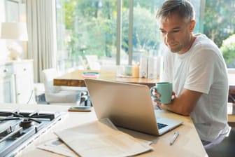 Mann mit Kaffee am Laptop