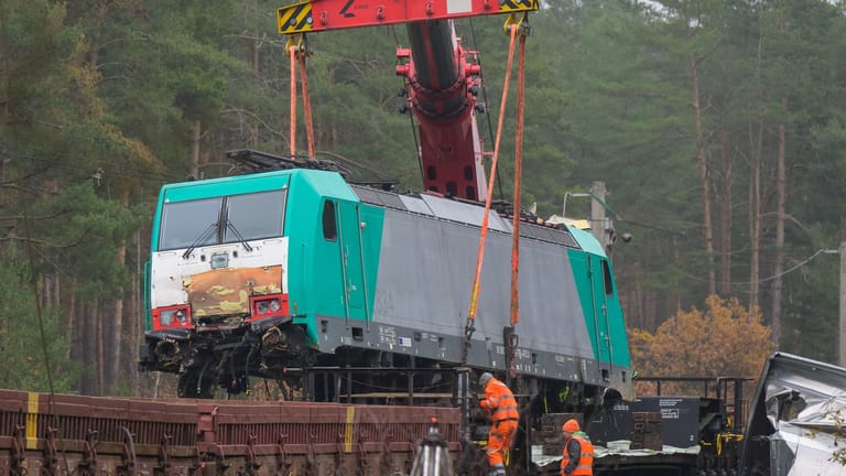 Die verunfallte Lok wird mit einem Kran auf einen Waggon gehoben. Nach einem Zugunfall auf der Bahnstrecke zwischen Hannover und Berlin gehen die Aufräumarbeiten weiter.