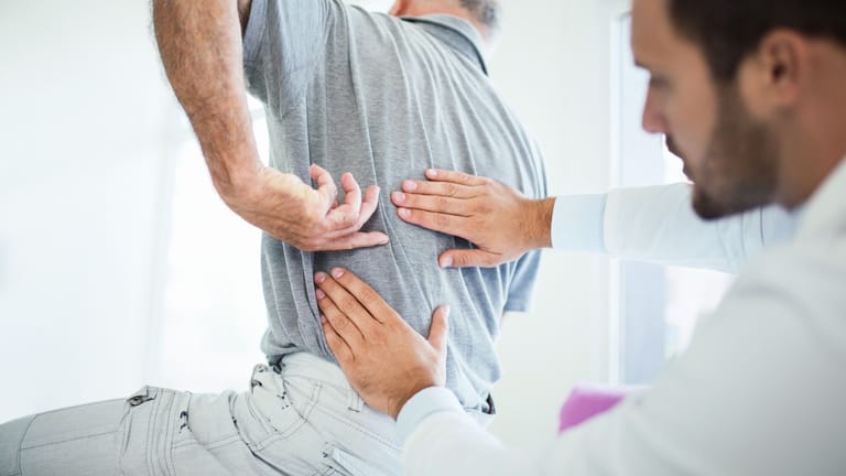 Mann mit Rückenschmerzen beim Arzt