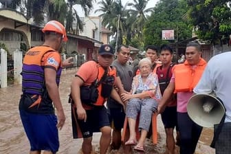 Eine ältere Frau wird von der Küstenwache in Sicherheit gebracht: Nach außergewöhnlichen Regenfällen gibt es in den Philippinen noch immer zahlreiche Vermisste.