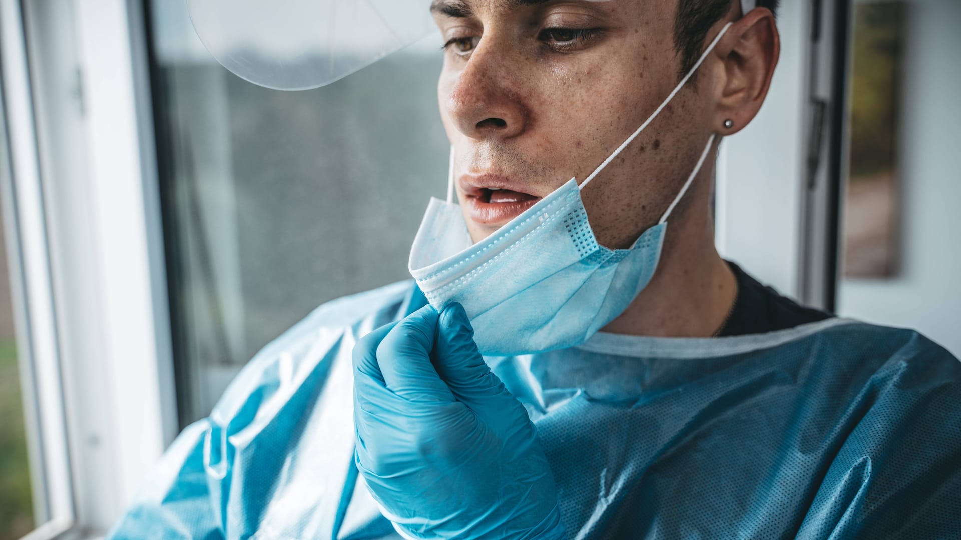 Ein Pfleger zieht sich erschöpft die Maske vom Gesicht (Symbolbild): Die Olgaklinik ist am Limit.