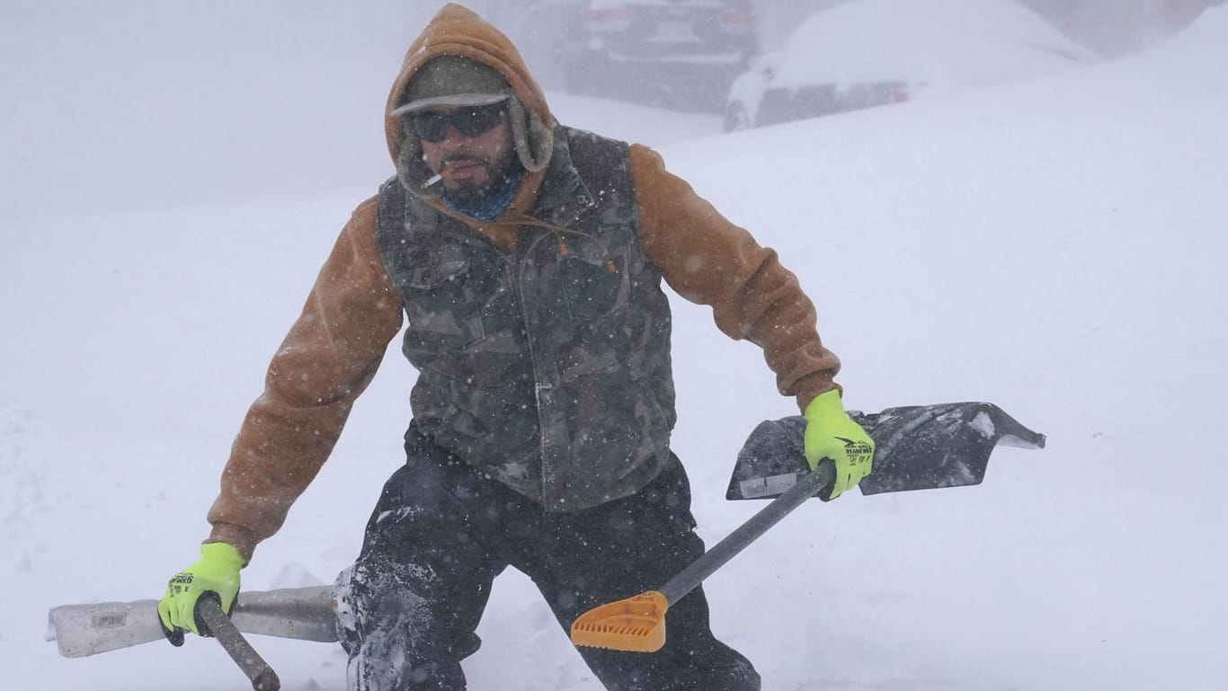 Travis Sanchez stapft mit zwei Schaufeln durch den Schnee in Buffalo, um einem gestrandeten Autofahrer zu helfen.