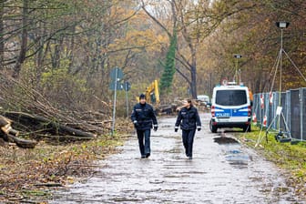 Einsatzkräfte der Polizei gehen an gerodeten Bäume neben dem gesperrten Südschnellweg (Bundesstraße 3) entlang.