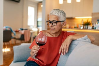 Eine Frau betrachtet nachdenklich ein Glas Wein.
