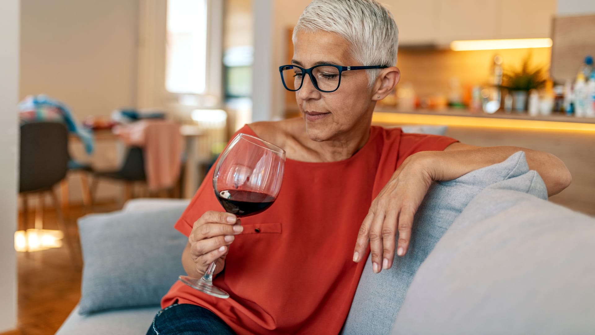 Eine Frau betrachtet nachdenklich ein Glas Wein.