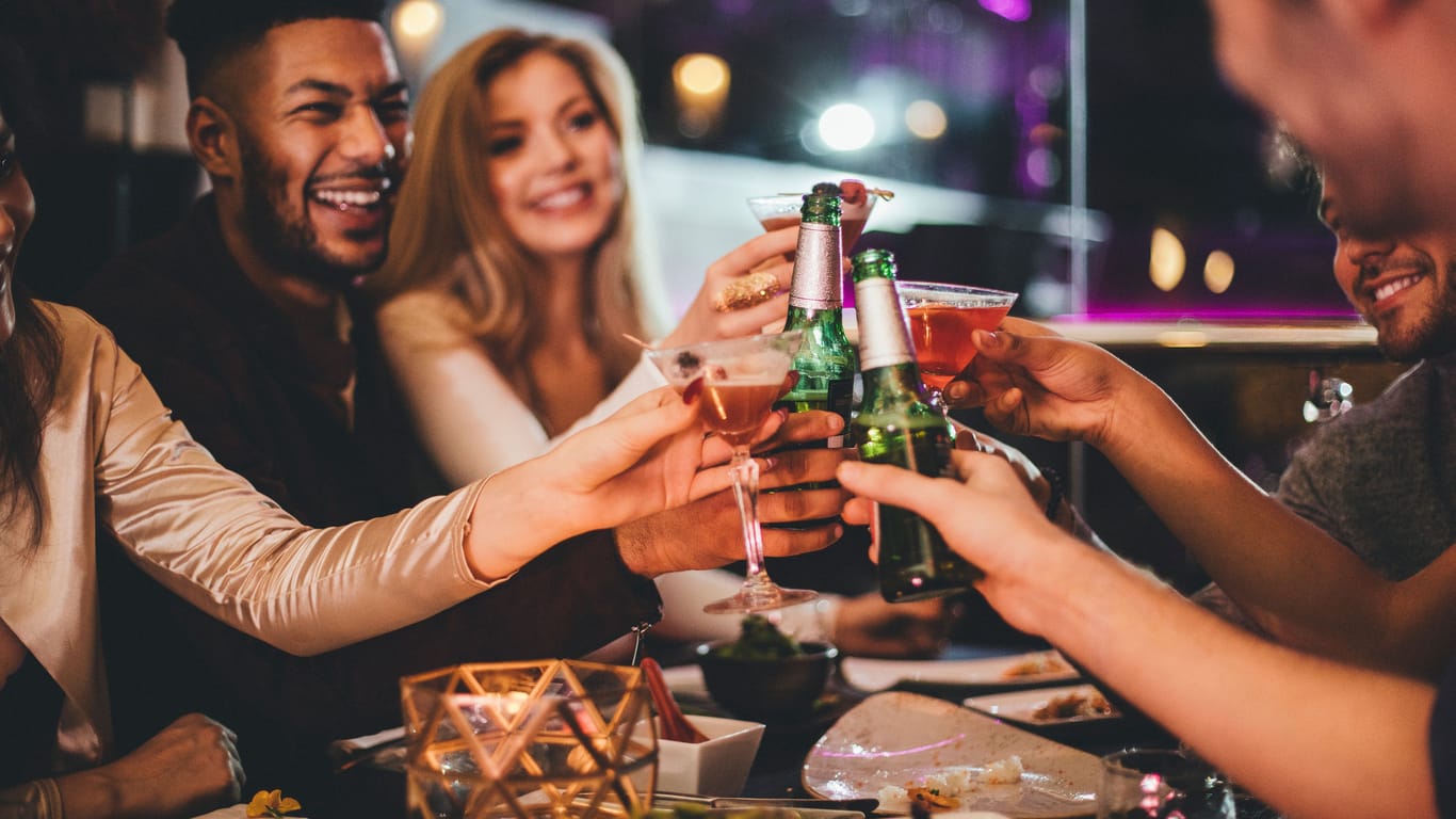 Eine Gruppe von Freunden stößt mit alkoholischen Getränken an.