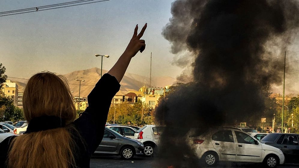 Eine Frau steht während einer Demonstration in Teheran vor einem brennenden Autoreifen (Archivbild): Auch im Süden des Landes wagen sich Frauen auf die Straße.