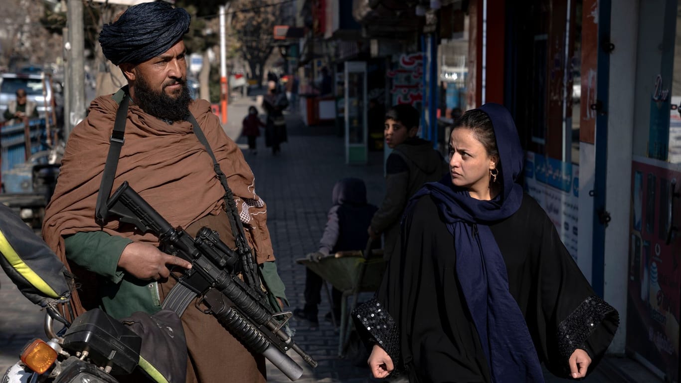 Ein Taliban-Kämpfer steht Wache, während eine Frau vorbeiläuft: Die jüngsten Entscheidungen der Taliban riefen massive Kritik hervor.