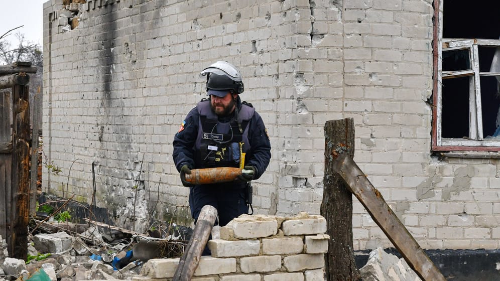 Ein ukrainischer Minenräumer hält nicht explodierte Munition in den Händen.