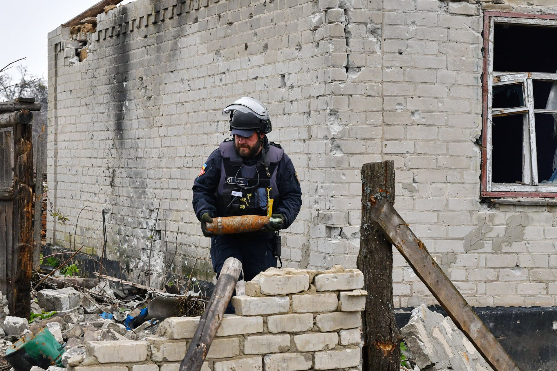 Ein ukrainischer Minenräumer hält nicht explodierte Munition in den Händen.