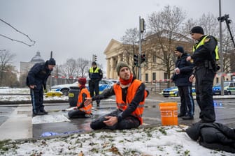 Zwei Klimaaktivisten nehmen an einer Protestaktion der Gruppe "Letzte Generation" teil, indem sie versuchen sich auf einer Straße festzukleben. Die Aktion fand trotz einer Allgemeinverfügung der Stadt München zu Klimaprotesten statt.