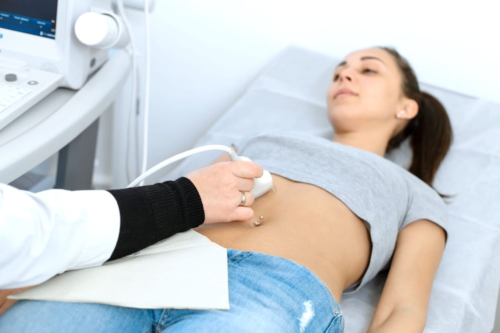 Eine Ärztin führt eine Ultraschalluntersuchung des Oberbauchs bei einer Patientin durch.