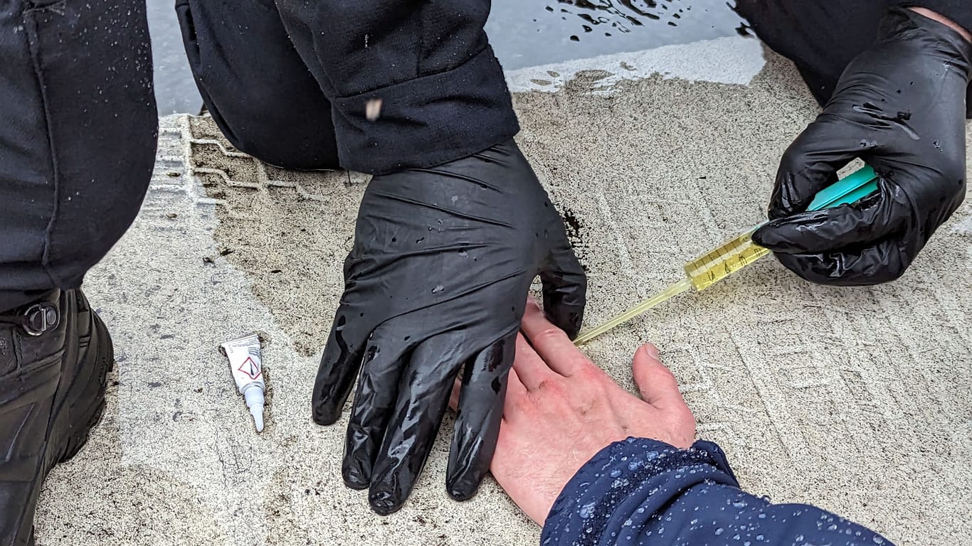 Ein Polizist versucht die Hand eines Aktivisten von der Straße zu lösen: Das Lösungsmittel stellte sich als Olivenöl aus der Metro heraus.