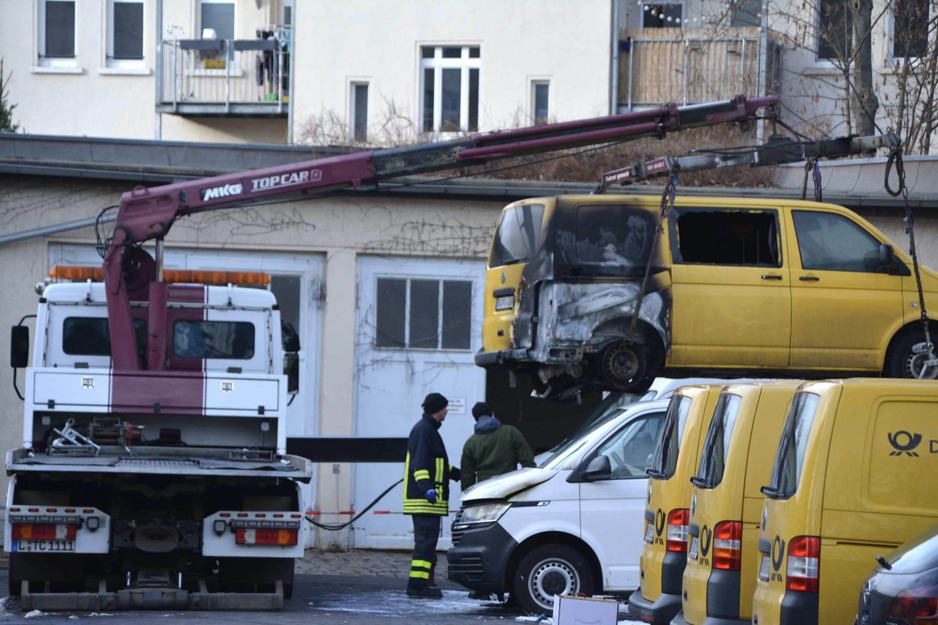 Ein Abschleppdienst holt die Fahrzeugwracks ab: Mehrere Post-Autos wurden am Montag in Brand gesetzt.
