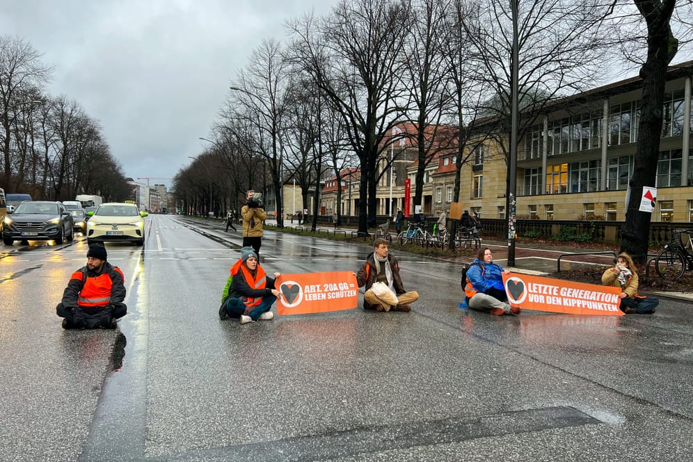 Mehrere Aktivisten der Gruppe "Letzten Generation" blockieren die Edmund-Siemers-Allee in Hamburg.