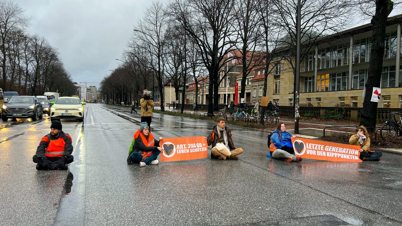 Mehrere Aktivisten der Gruppe "Letzten Generation" blockieren die Edmund-Siemers-Allee in Hamburg.