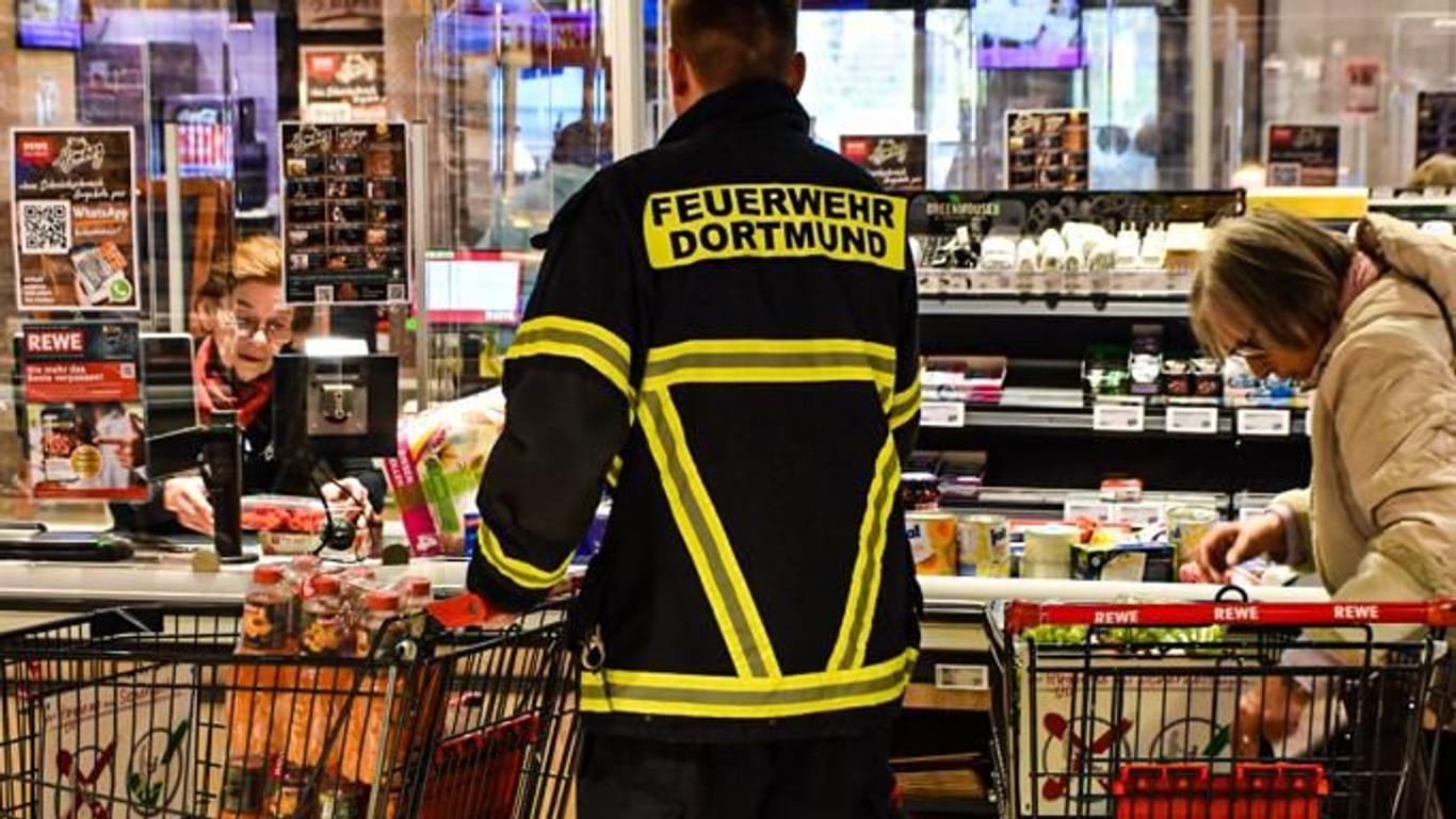 Einsatzkräfte der Feuerwehr an der Supermarkt-Kasse: In Dortmund haben sie ab sofort Vorfahrt.