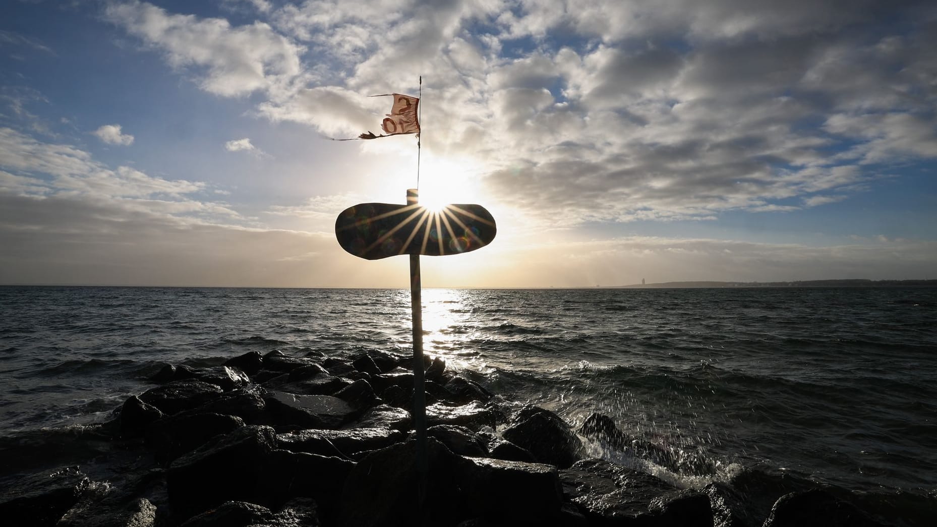 Die Sonne strahlt hinter einem Holzschild (Archvibild): An der See werden Sturmböen erwartet.