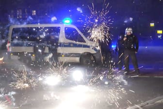 Polizeibeamte stehen hinter explodierendem Feuerwerk: Nach Angriffen auf Einsatzkräfte in der Silvesternacht hat die Diskussion um Konsequenzen begonnen.