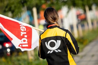 Eine Postangestellte hält eine Verdi-Fahne (Archivfoto): Die Gewerkschaft fordert 15 Prozent mehr Lohn.