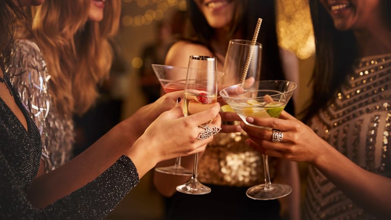 Eine Gruppe Frauen stößt mit Cocktails und Sekt an.