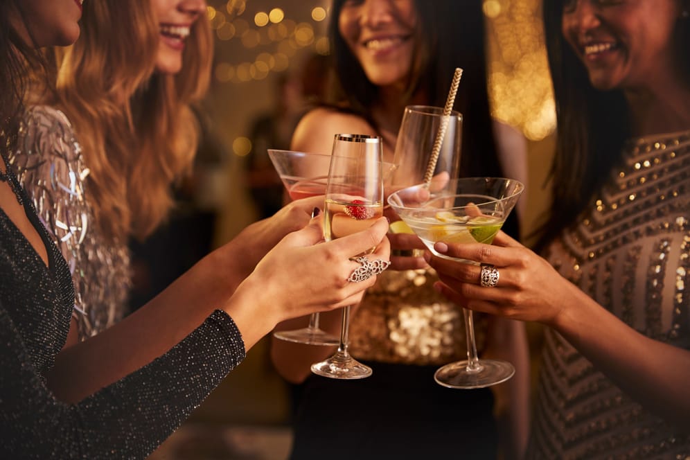 Eine Gruppe Frauen stößt mit Cocktails und Sekt an.