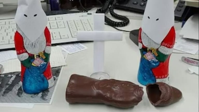 Empörende Aktion im Ordnungsamt: Zwei Schoko-Nikoläuse mit weißen Kapuzen des Ku-Klux-Klans. Davor liegt ein enthüllter Schoko-Nikolaus.