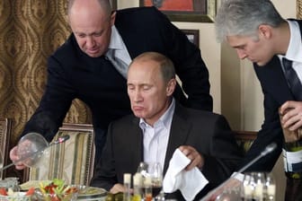 Jewgeni Prigoschin (l.) präsentiert Kremlchef Putin (M.) eine Mahlzeit: Noch immer verdient "Putins Koch" viel Geld mit seinen 22 Catering-Firmen.