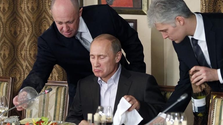Jewgeni Prigoschin (l.) präsentiert Kremlchef Putin (M.) eine Mahlzeit: Noch immer verdient "Putins Koch" viel Geld mit seinen 22 Catering-Firmen.