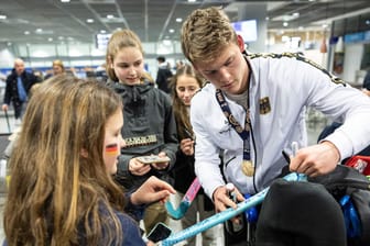 Jean-Paul Dannenberg unterschreibt auf einem Hockey-Schläger: Nach dem Sieg gegen die belgische Feldhockey Mannschaft wurde die deutsche Nationalmannschaft von Fans am Frankfurter Flughafen empfangen.
