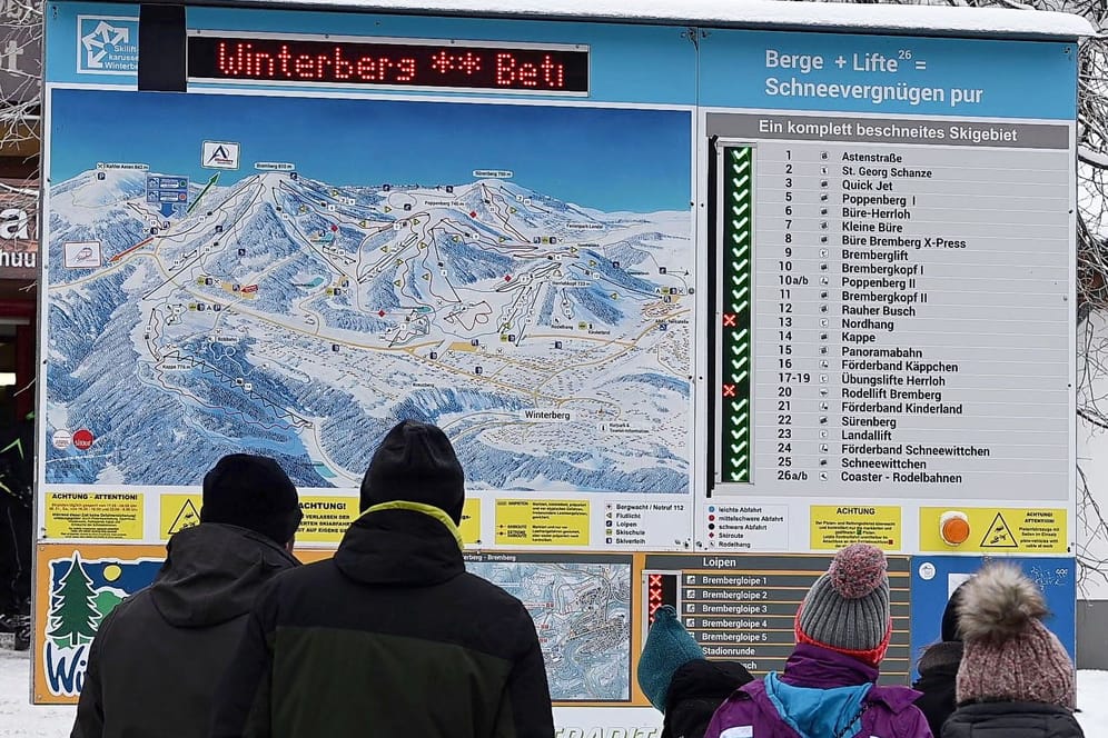 Winterberg: Skifahrer stehen vor einer Anzeigetafel, die überwiegend geöffnete Pisten ausweist. Im Sauerland gibt es nach wochenlangem Tauwetter wieder gute Wintersportbedingungen.