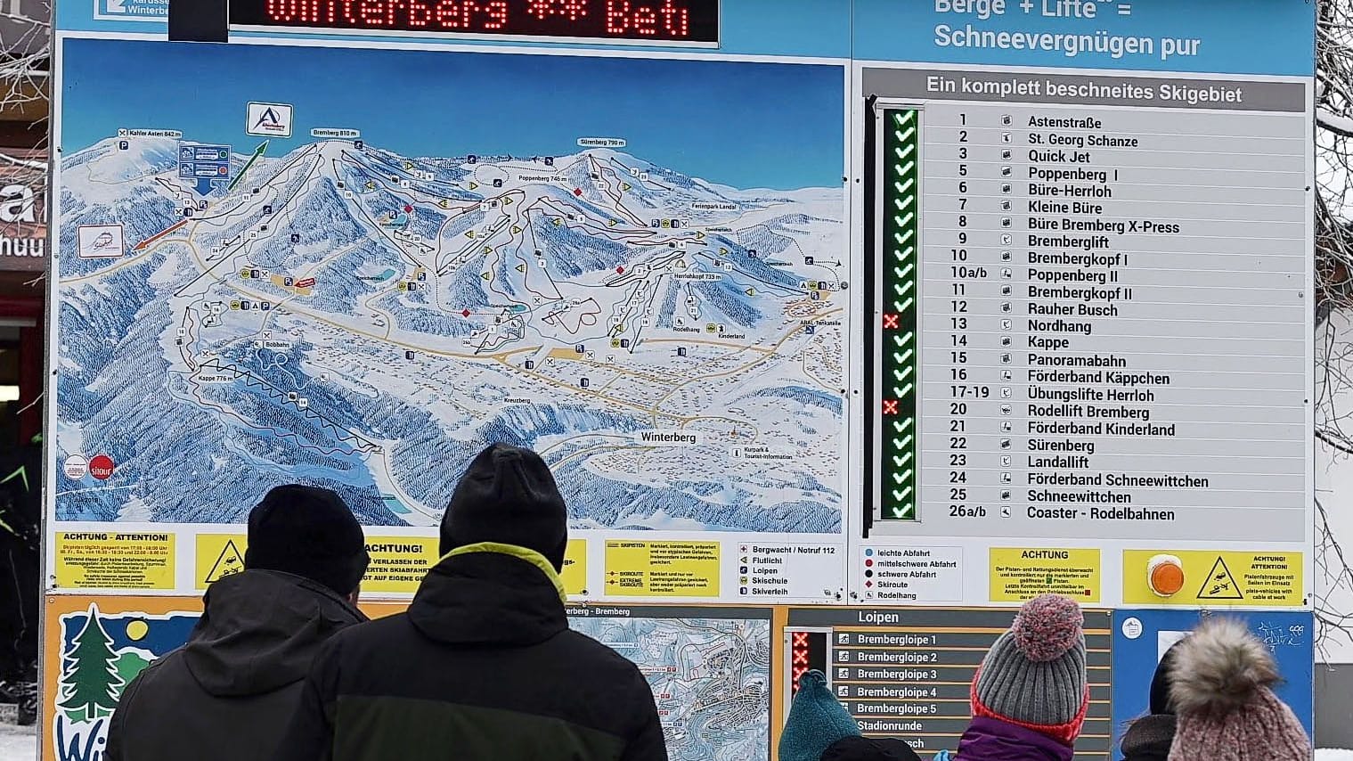 Winterberg: Skifahrer stehen vor einer Anzeigetafel, die überwiegend geöffnete Pisten ausweist. Im Sauerland gibt es nach wochenlangem Tauwetter wieder gute Wintersportbedingungen.