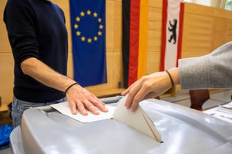 Eine Person wirft einen Stimmzettel in ein Box (Archivbild): Wie geht es nun mit der Berlin-Wahl weiter?