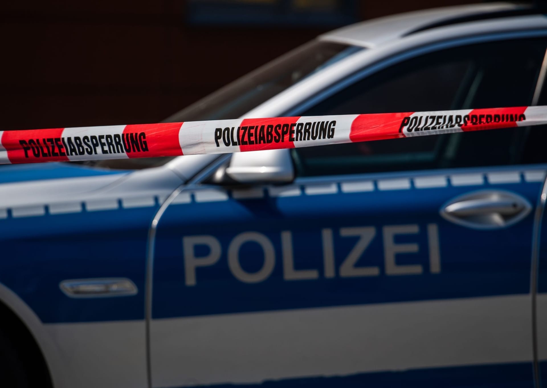 Ein Polizeiauto steht hinter einem Absperrband der Polizei (Symbolbild): In Bremen kam es zu einem tödlichen Betriebsunfall.