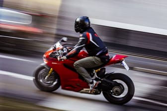 Ein Motorradfahrer fährt eine Straße entlang (Symbolfoto): Der Fahrer entkam unerkannt.