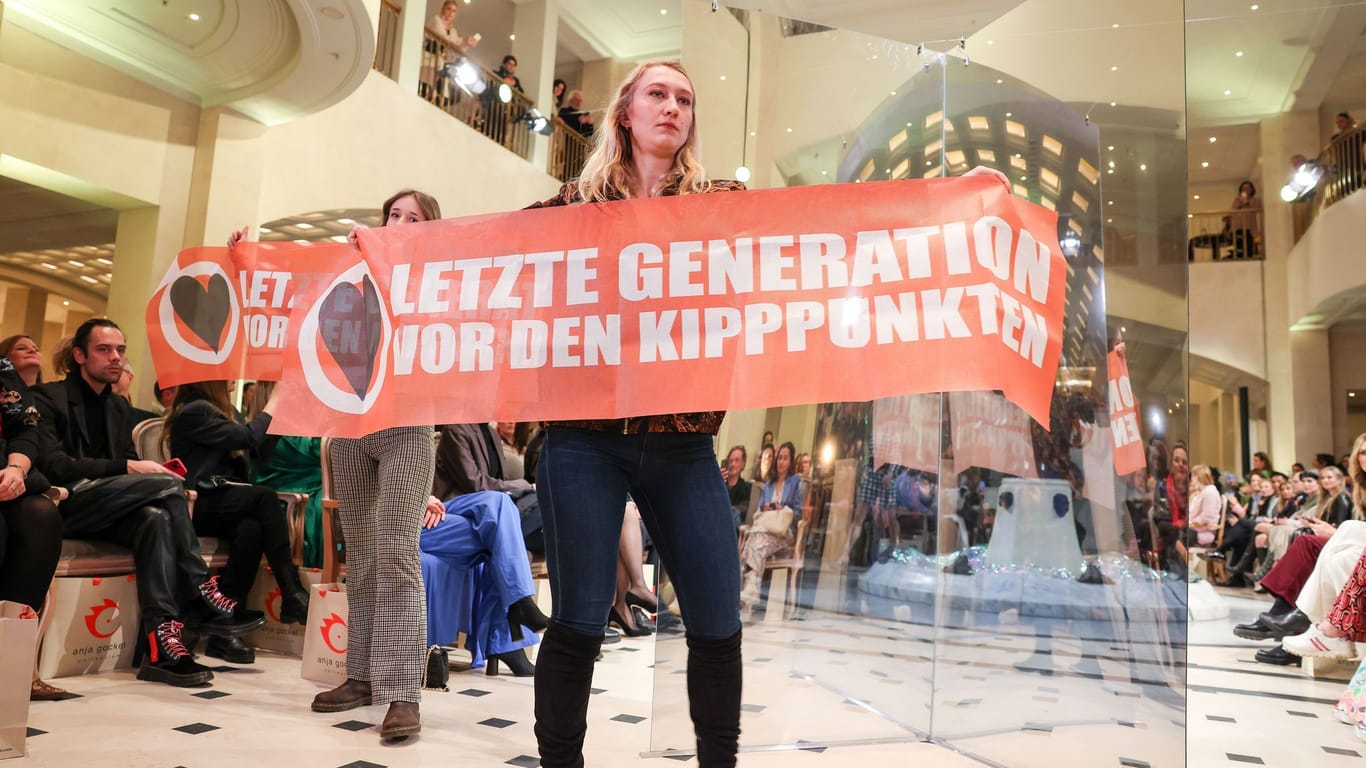 Die beiden Demonstrantinnen halten Transparente hoch: Die Berliner Modewoche findet vom 16. bis 21. Januar statt.