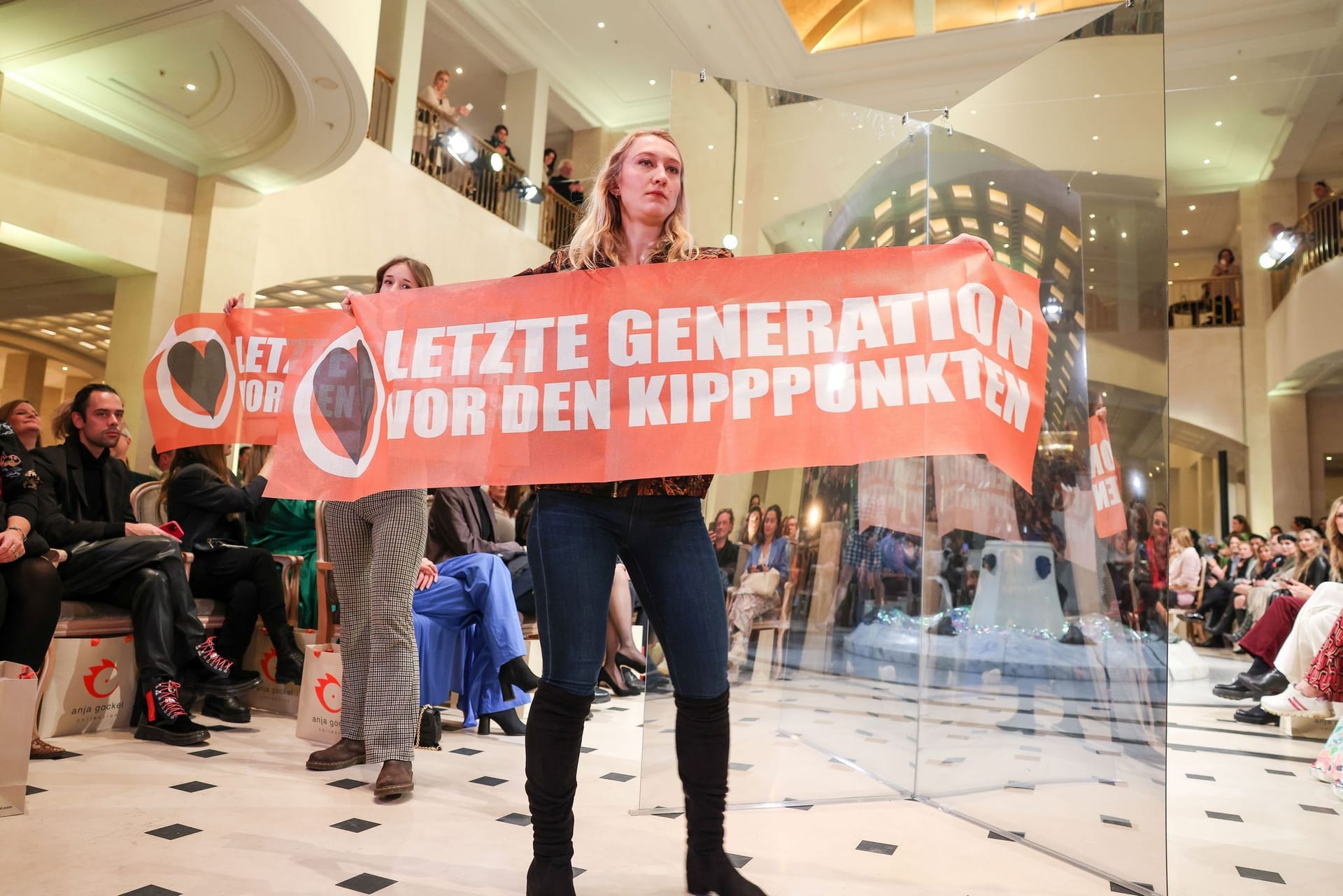 Die beiden Demonstrantinnen halten Transparente hoch: Die Berliner Modewoche findet vom 16. bis 21. Januar statt.