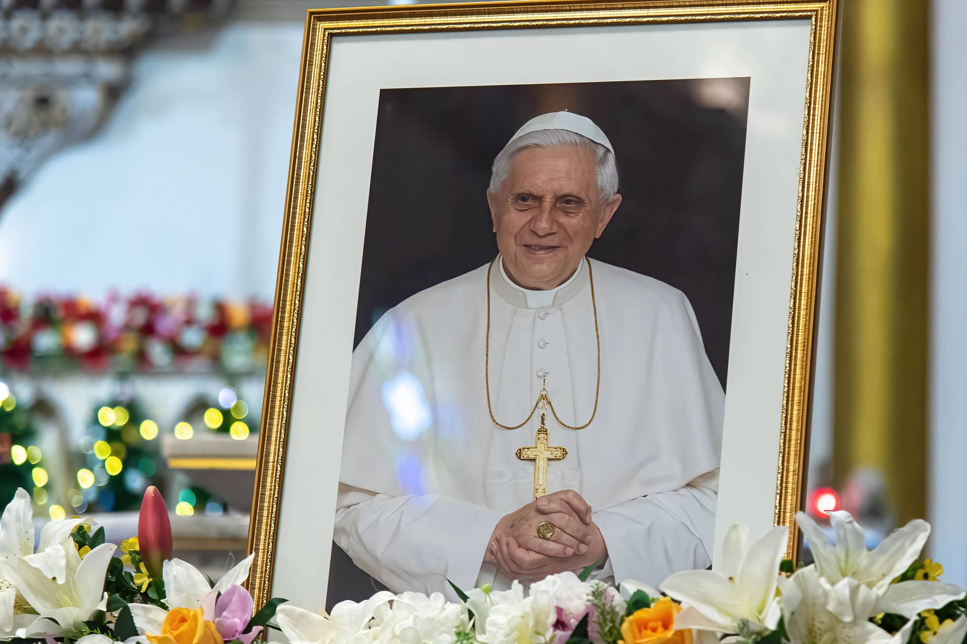 Ein Bild des verstorbenen Benedikt XIV. in einer Kirche: Zur Trauerfeier am Donnerstag haben sich zahlreiche namhafte Politikerinnen und Politiker angekündigt.